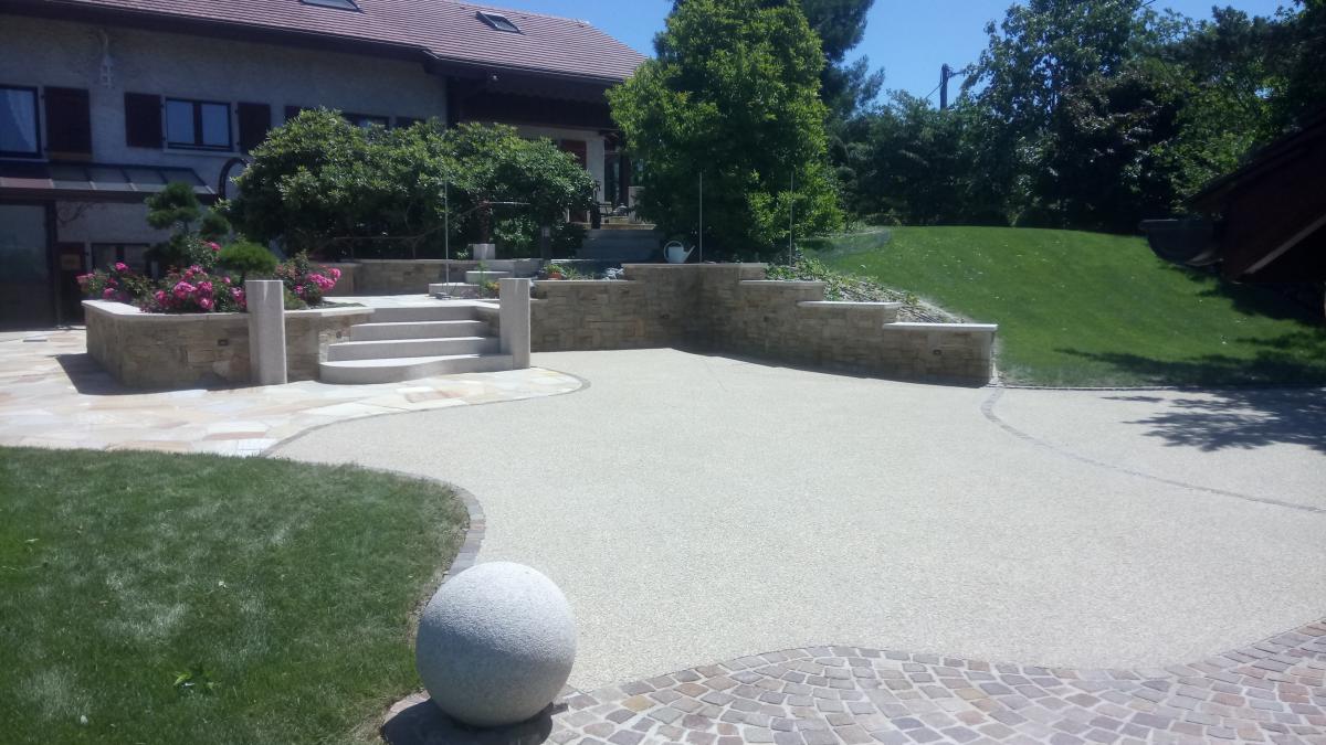 Cour en béton désactivé réalisé vers Annemasse, avec lignes de pavés en pierre, et terrasses en dallage à proximité.