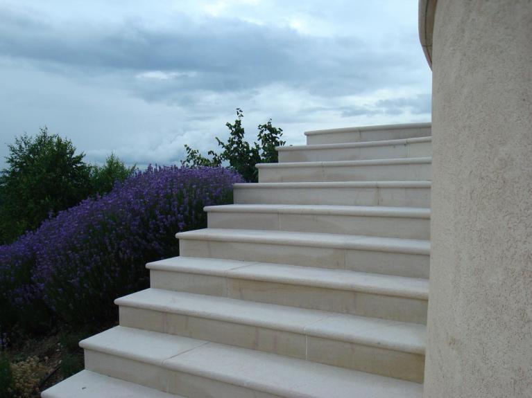 Escaliers de jardin en pierre massive, avec nez de marche en demi-rond. Escaliers en pierre calcaire de couleur beige crême, avec des veines de pierre rouge rosé. Réalisation de l'escalier à Le Lyaud.