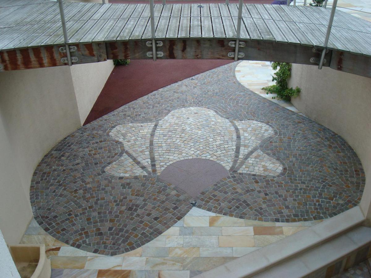 Terrasse en forme de coeur réalisée à Thonon. Le coeur est fait fait en pavés de pierre de couleur rouge brun. Le centre du coeur est en pavés beige jaune.