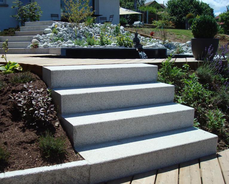 Escaliers droits, en blocs de pierre naturelle gris moucheté. Pierre Granit gris clair. Nez de marche chamfreiné