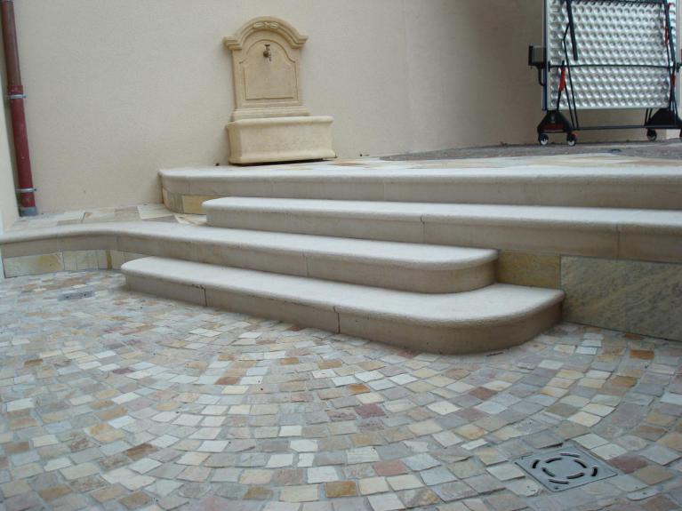 Escaliers de jardin larges, composés de plusieurs blocs taillés en arrondis. Escaliers beiges, en pierre calcaire. Réalisation paysagiste à Thonon